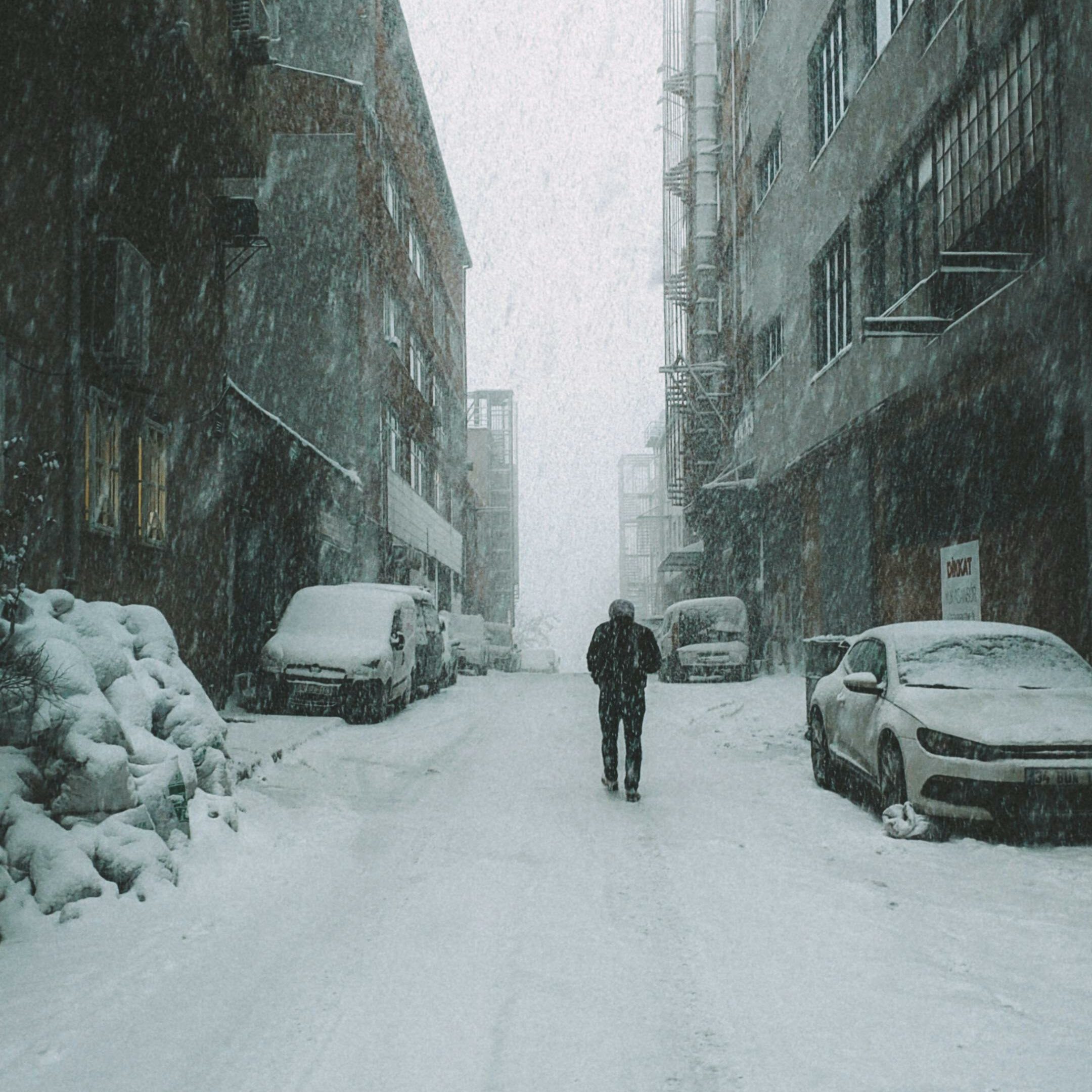 un homme seul marche dans une rue enneigée